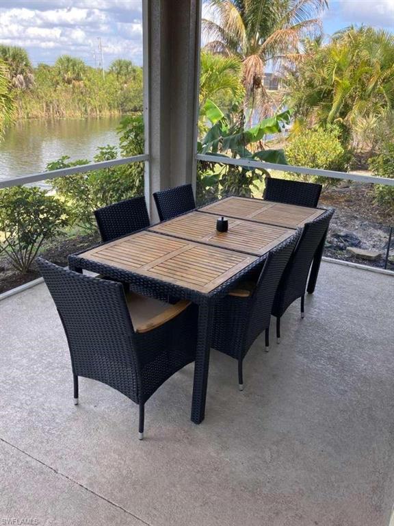 Screened patio featuring concrete flooring and a tranquil water view surrounded by lush tropical landscaping