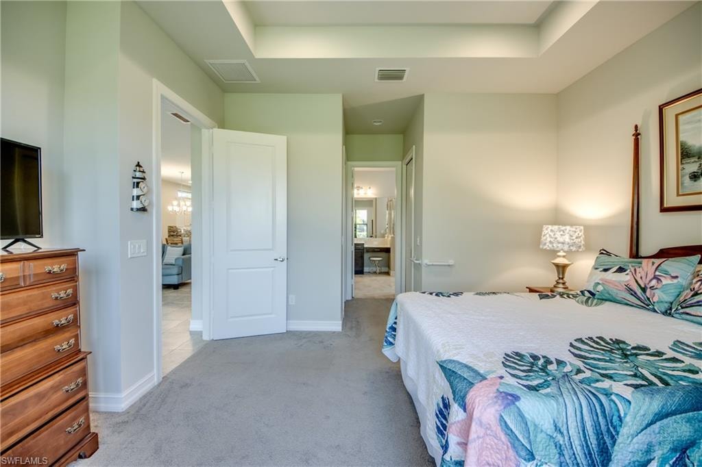 Carpeted bedroom featuring a tray ceiling and light-toned wall paint