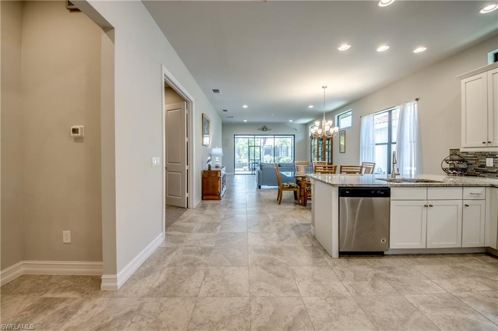 Open-concept living area featuring light-toned tile flooring, recessed lighting, and white baseboards