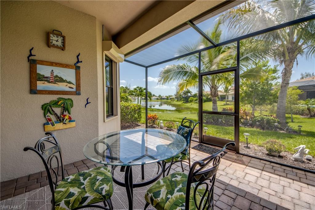 Screened lanai featuring paver flooring, a glass-top table, and direct access to the outdoor space