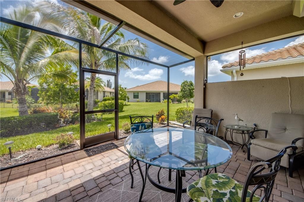 Screened-in patio featuring brick paver flooring, a vaulted ceiling, and a full-height privacy wall