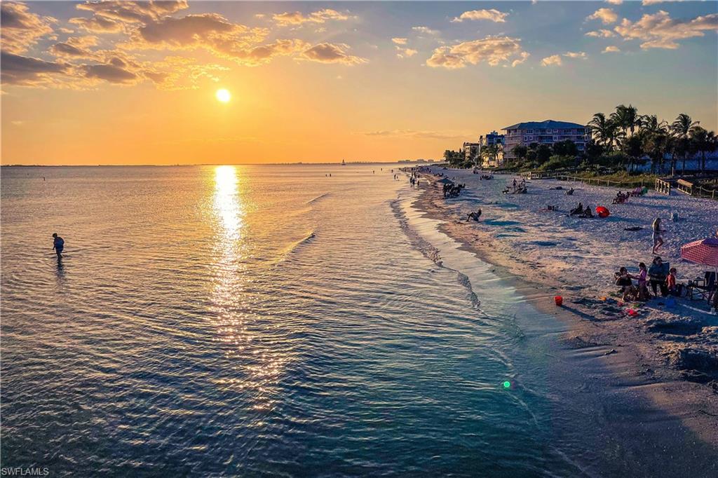 Beachfront property featuring multi-story buildings, palm trees, and direct access to a sandy shoreline and ocean