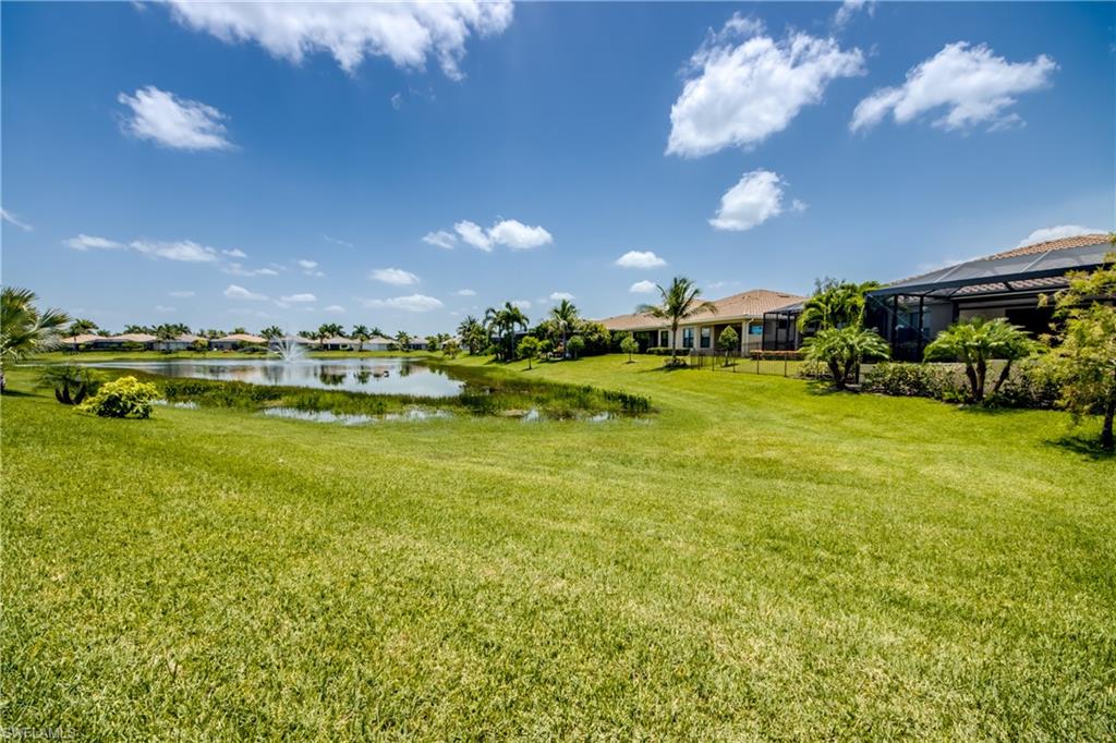 Expansive green lawn bordering a tranquil pond with a decorative fountain