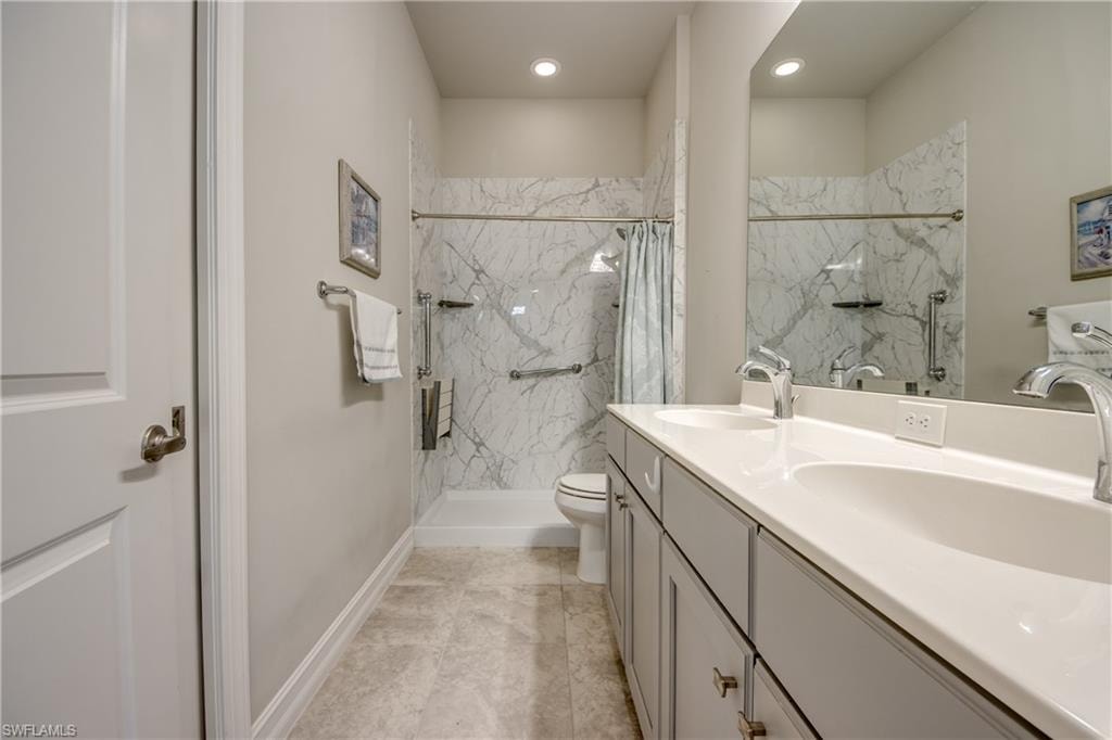 Bathroom featuring a double vanity with integrated sinks, a wide mirror, and grey cabinet storage