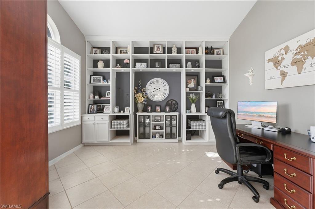 Custom built-in shelving with integrated cabinetry, plantation shutters, tiled flooring, and a high ceiling