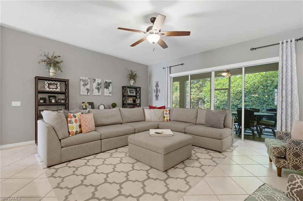 Spacious room featuring tile flooring, ceiling fan, and large sliding glass doors opening to an outdoor patio with screening