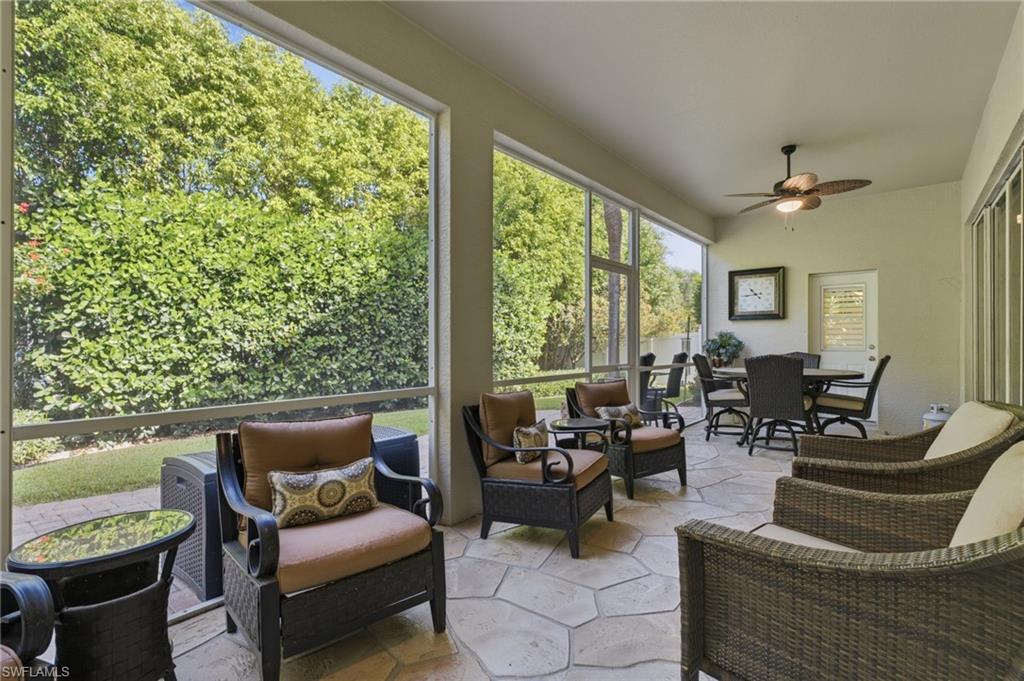 Screened patio featuring irregular-cut stone flooring, a ceiling fan with integrated lighting, and multiple sliding glass door panels