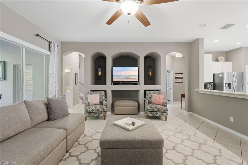 Spacious living area featuring a built-in media center with arched display niches, recessed lighting, and a ceiling fan