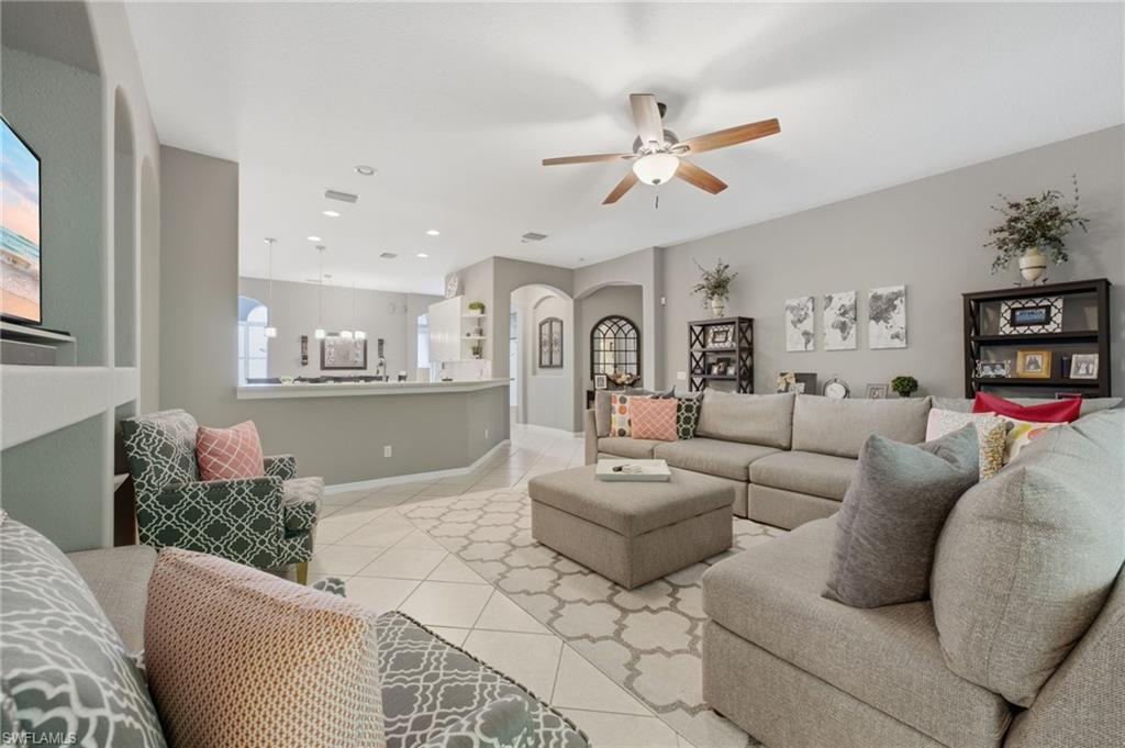 Spacious living area featuring tile flooring, a ceiling fan, recessed lighting, and a built-in wall niche with arched accents