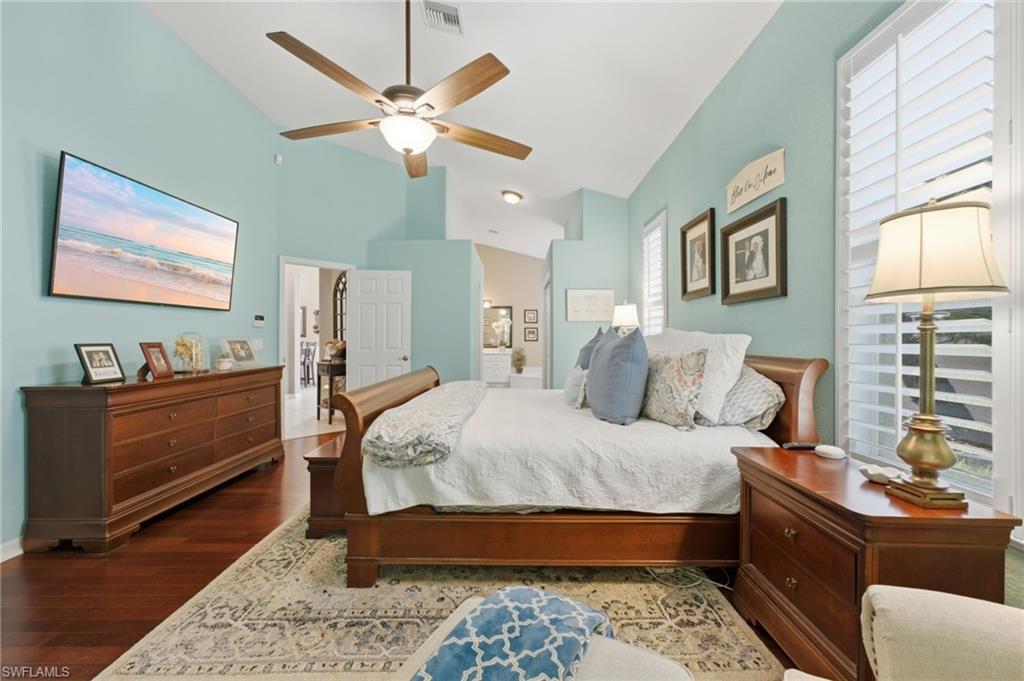 Interior bedroom featuring vaulted ceilings, wood-finish flooring, and light blue wall tones
