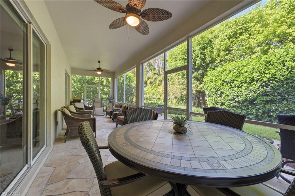 Expansive screened patio featuring flagstone-style flooring, multiple ceiling fans, and sliding glass doors