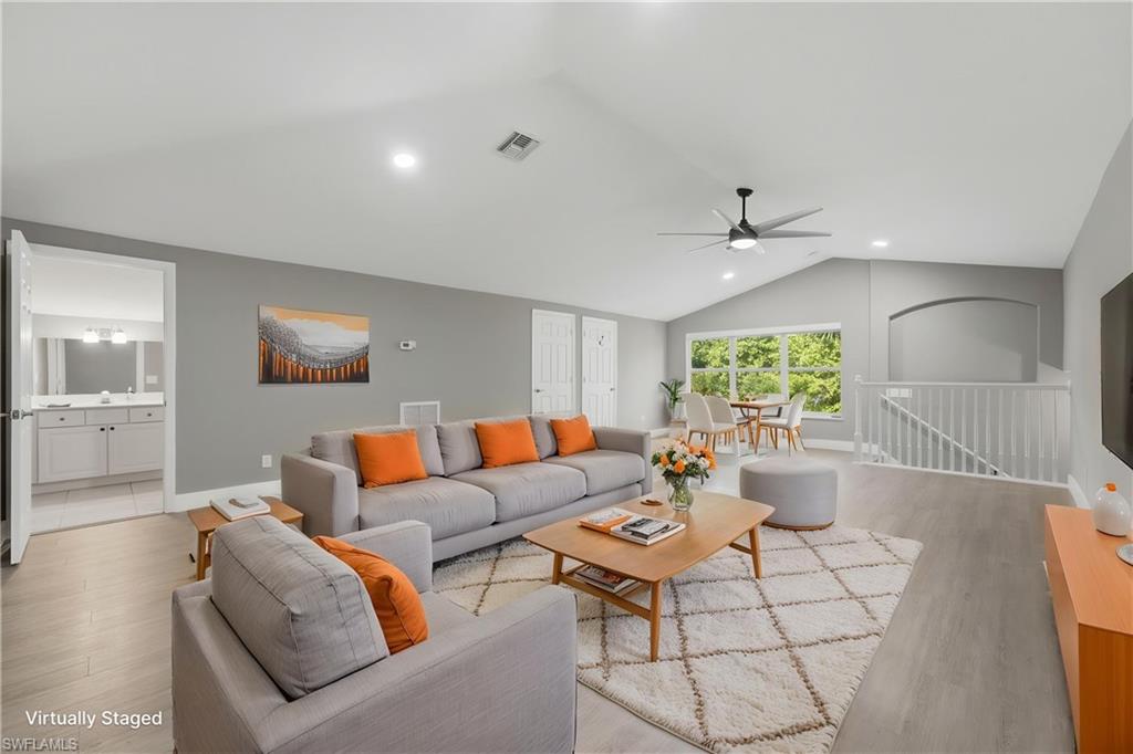 *VIRTUALLY STAGED* Expansive living area with vaulted ceilings and light wood-finish flooring
