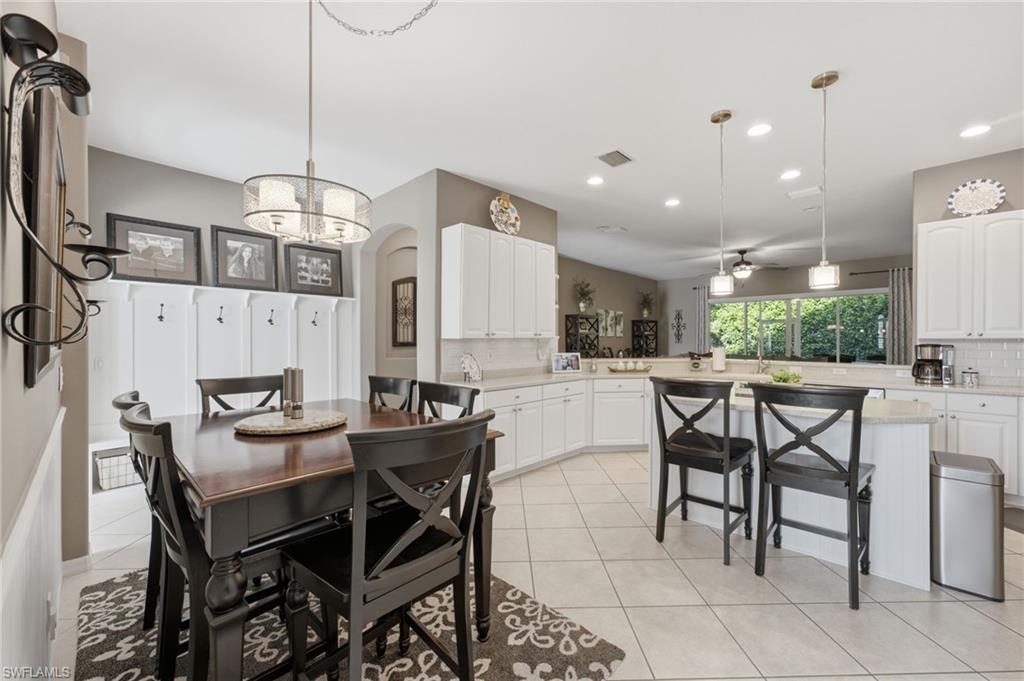 Open-concept kitchen and dining area featuring white cabinetry, light-toned countertops, and tile flooring