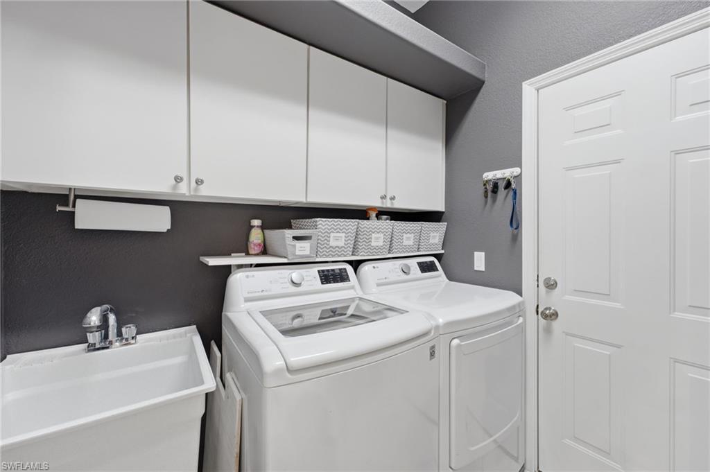 Dedicated laundry area featuring a utility sink with chrome faucet, upper white cabinetry, and a white paneled door