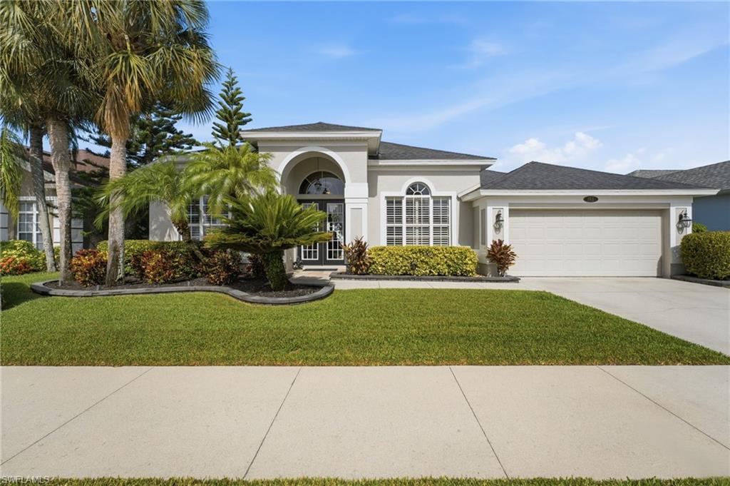 Stucco exterior with an arched entryway, double front doors, an arched window, and an attached two-car garage