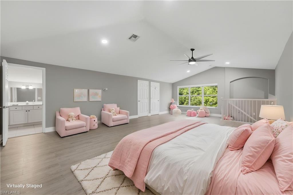 Spacious room featuring vaulted ceilings, light wood-finish flooring, a contemporary ceiling fan, and recessed lighting
