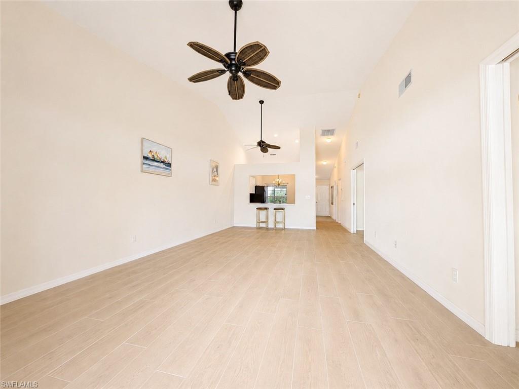 Vaulted ceilings enhance this expansive room featuring light-toned wood-finish flooring