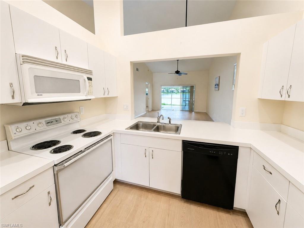 Modern kitchen featuring white cabinetry, light countertops, an electric range, built-in microwave, and a stainless steel double sink