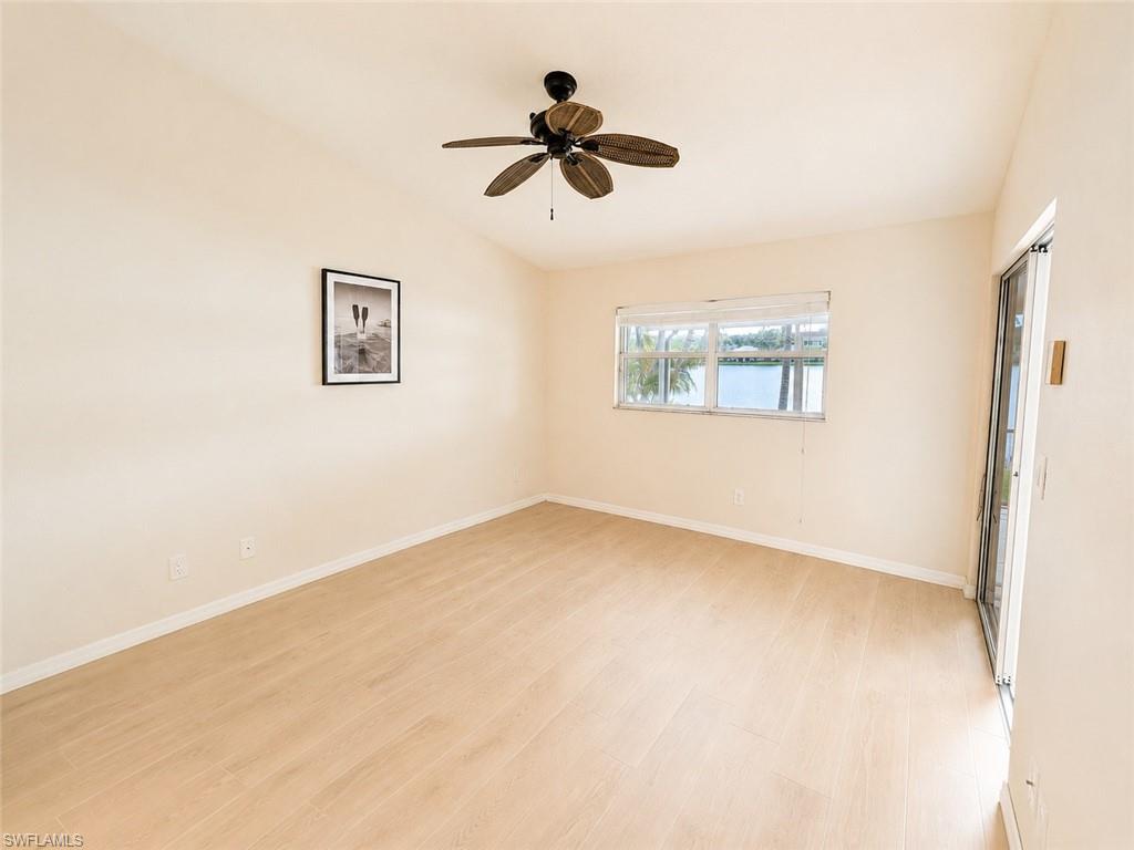 Bright interior space featuring light wood-finish flooring, a ceiling fan, and ample natural light from a window overlooking a body of water