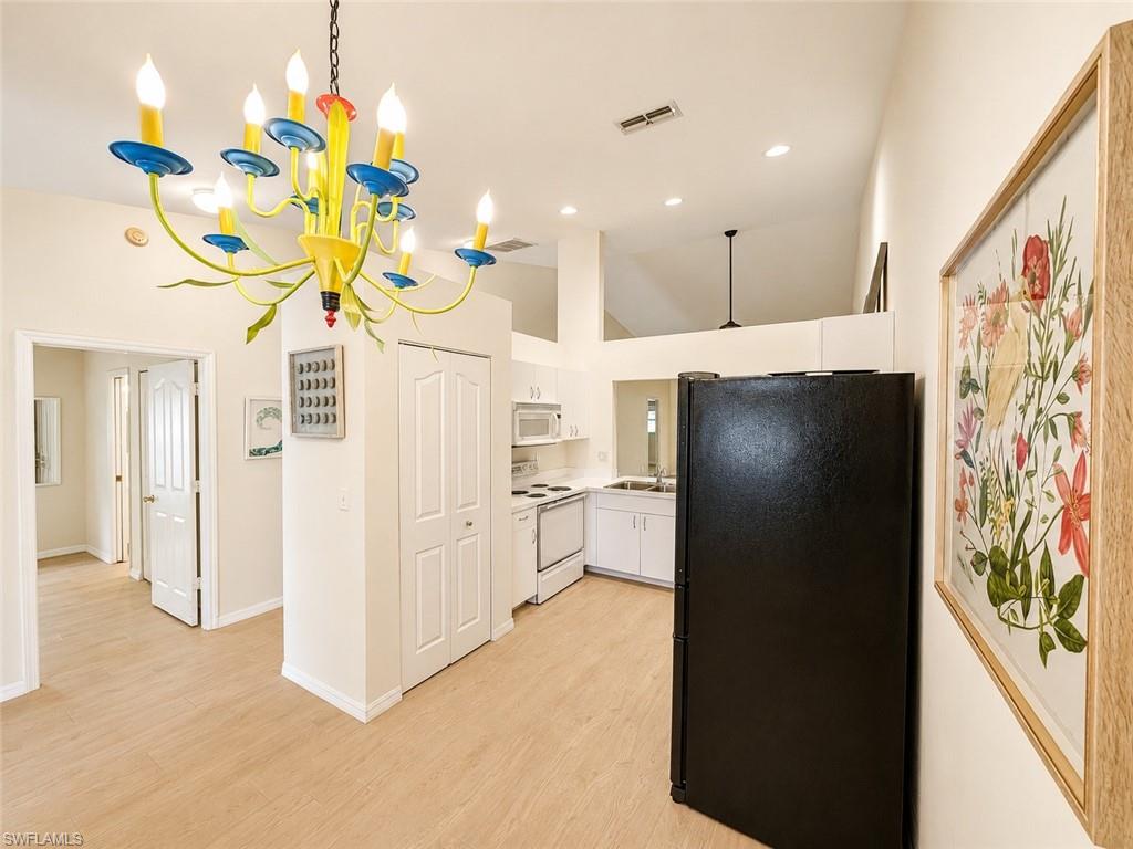 Kitchen area featuring a black refrigerator, white cabinetry, and a white electric range