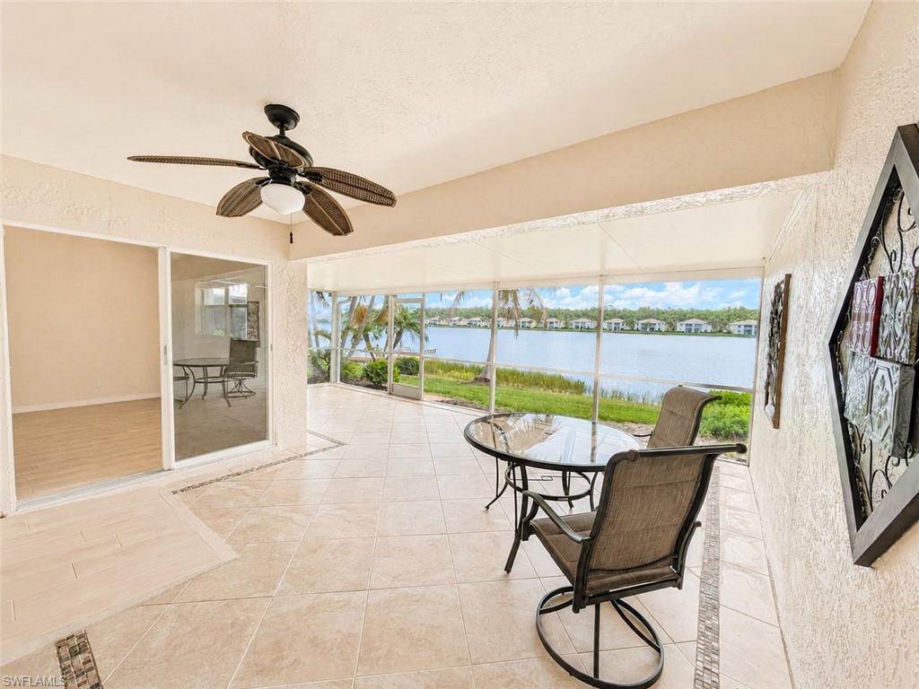 Screened patio featuring ceramic tile flooring with decorative inlay, a ceiling fan with integrated lighting, and expansive water frontage