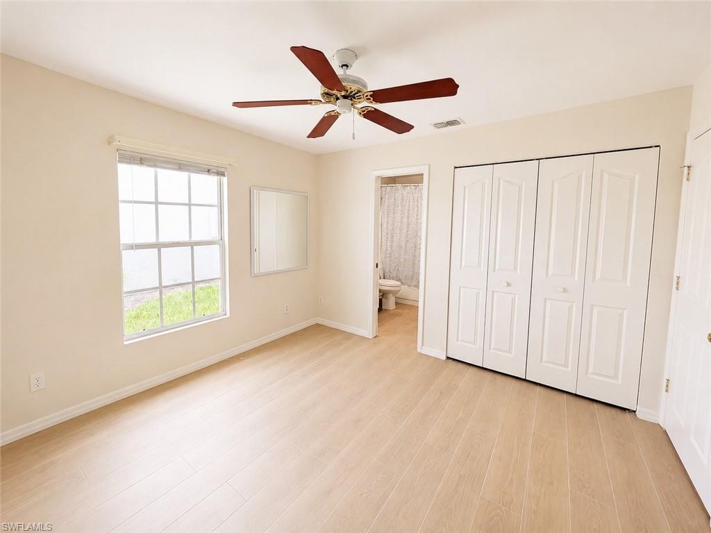 Neutral-toned room featuring light wood-finish flooring and a ceiling fan with dark wood blades