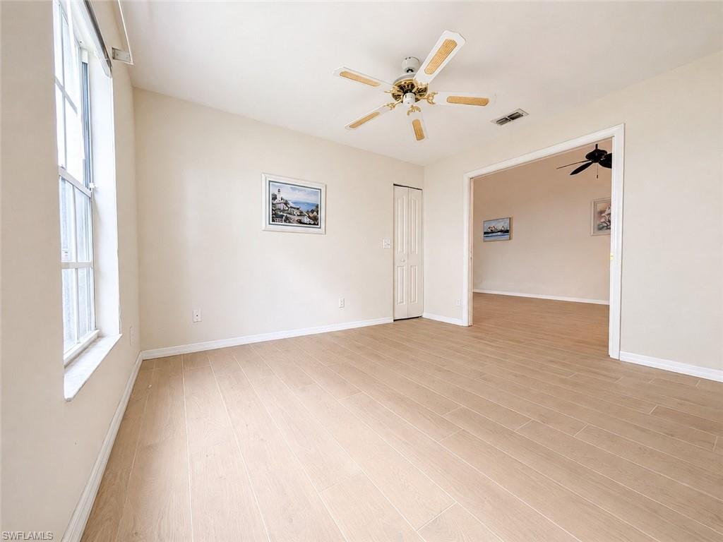 Spacious interior featuring light wood-finish flooring, vaulted ceilings, and a ceiling fan