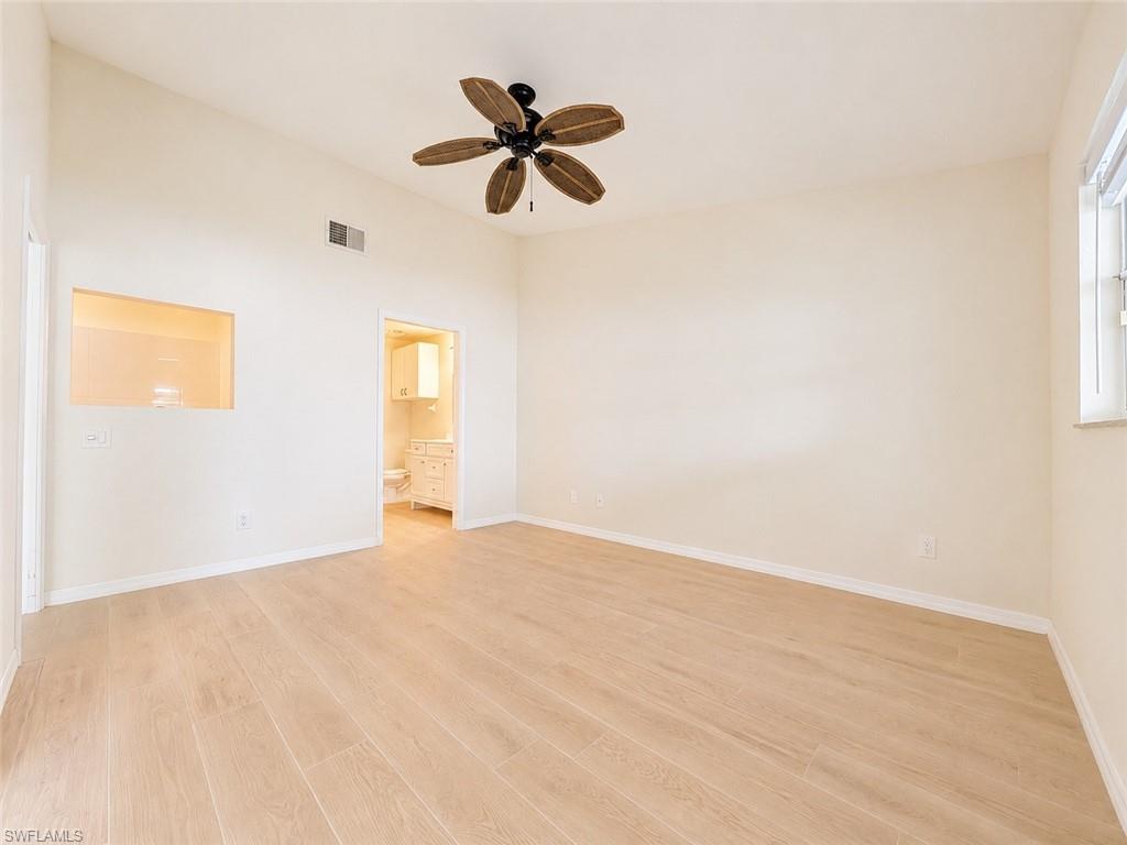 Spacious room featuring wood-finish flooring, a vaulted ceiling, and a ceiling fan with wood-look blades