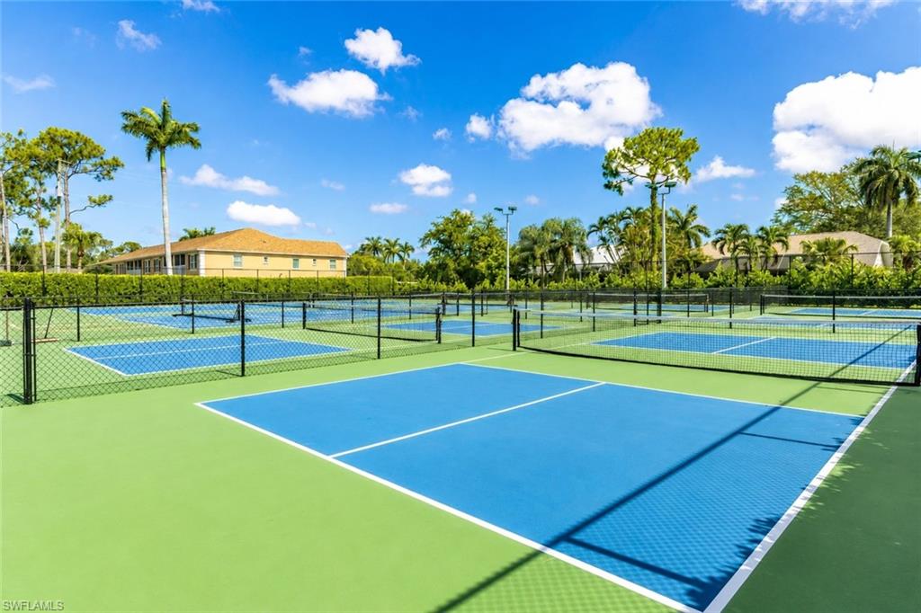 Multiple outdoor hard courts with blue playing surfaces and green surrounds