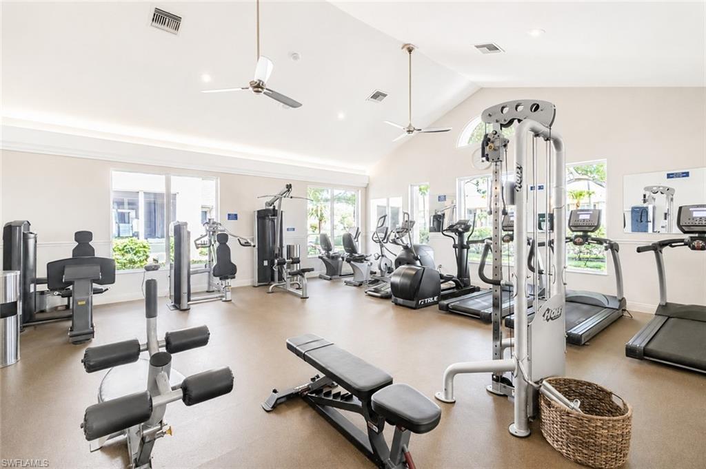 Fitness center with a vaulted ceiling, multiple windows, recessed lighting, and ceiling fans
