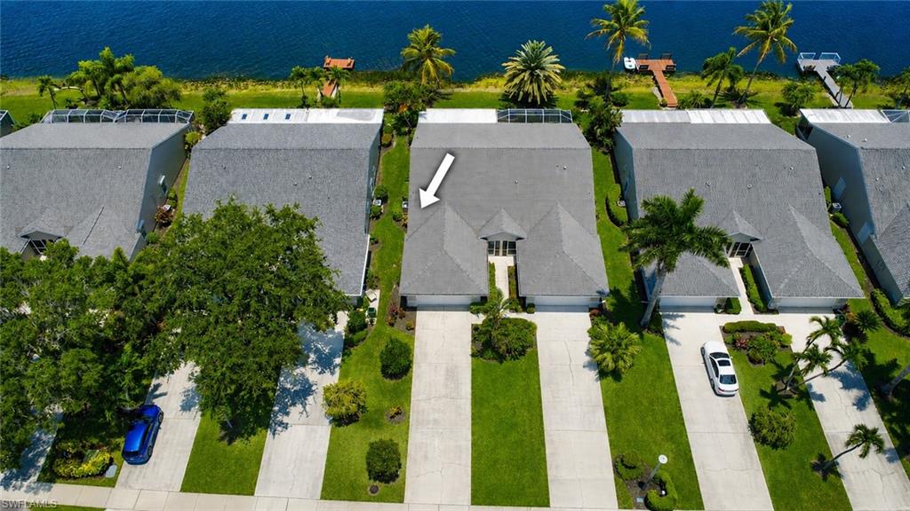 Waterfront property featuring a private dock, lush green landscaping, and an expansive paved driveway