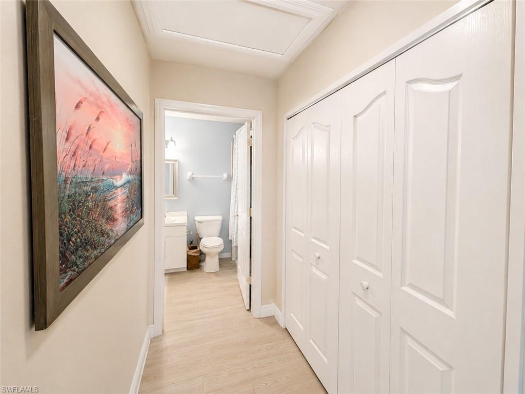 Hallway featuring light wood-finish flooring and a series of white bi-fold doors