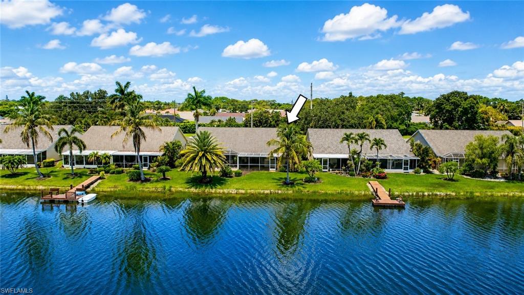 Waterfront property featuring a private dock, expansive green space, and mature palm trees
