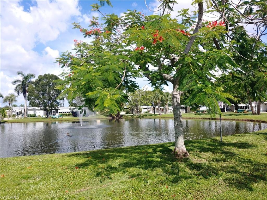 Expansive green lawn bordering a serene pond with a central fountain