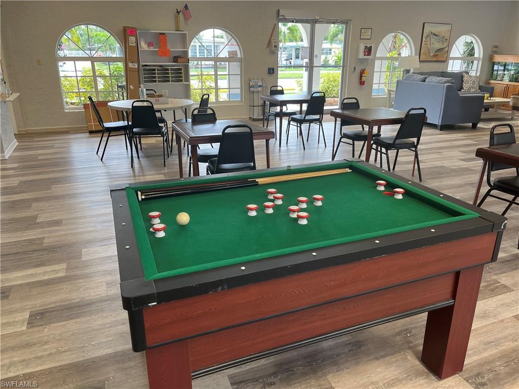 Spacious common area featuring wood-finish flooring, multiple arched windows, and a billiards table