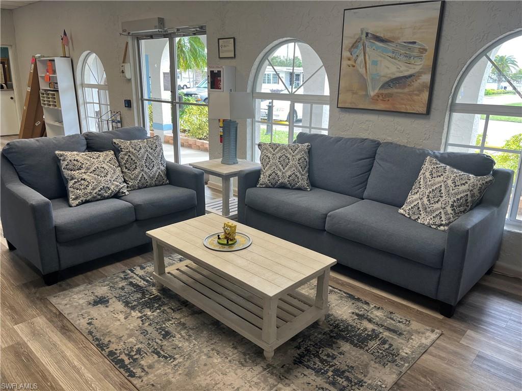 Open-concept interior featuring wood-finish flooring, arched windows, and a glass-paneled entry door