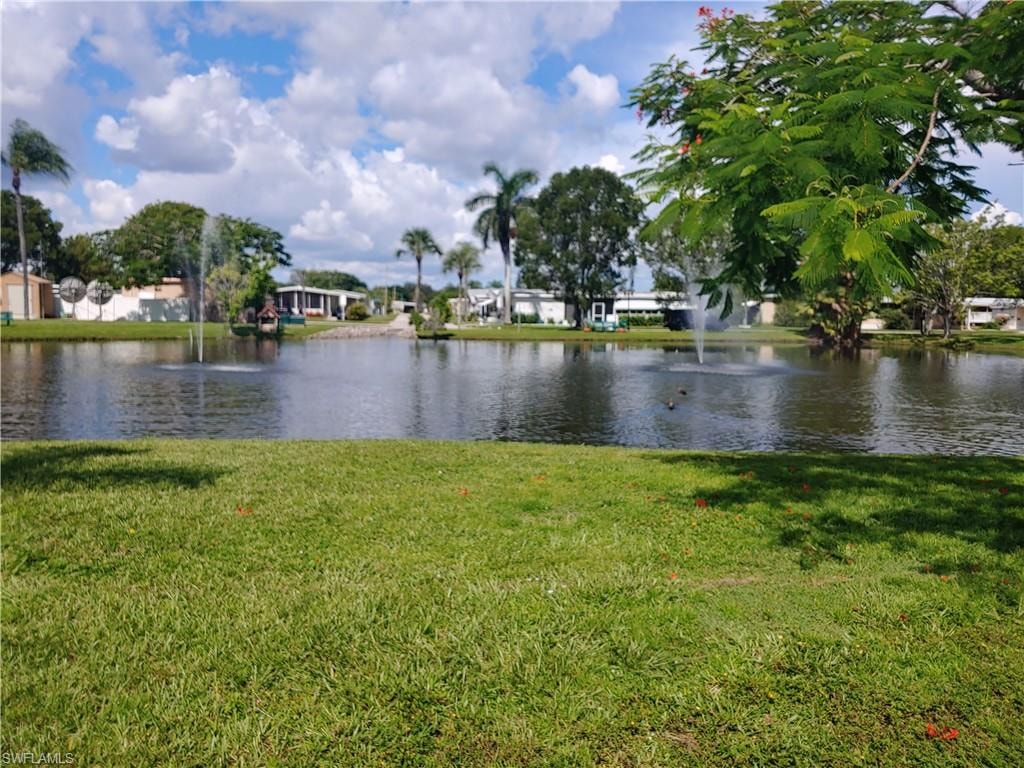 Lush green lawn bordering a tranquil pond with multiple water fountains