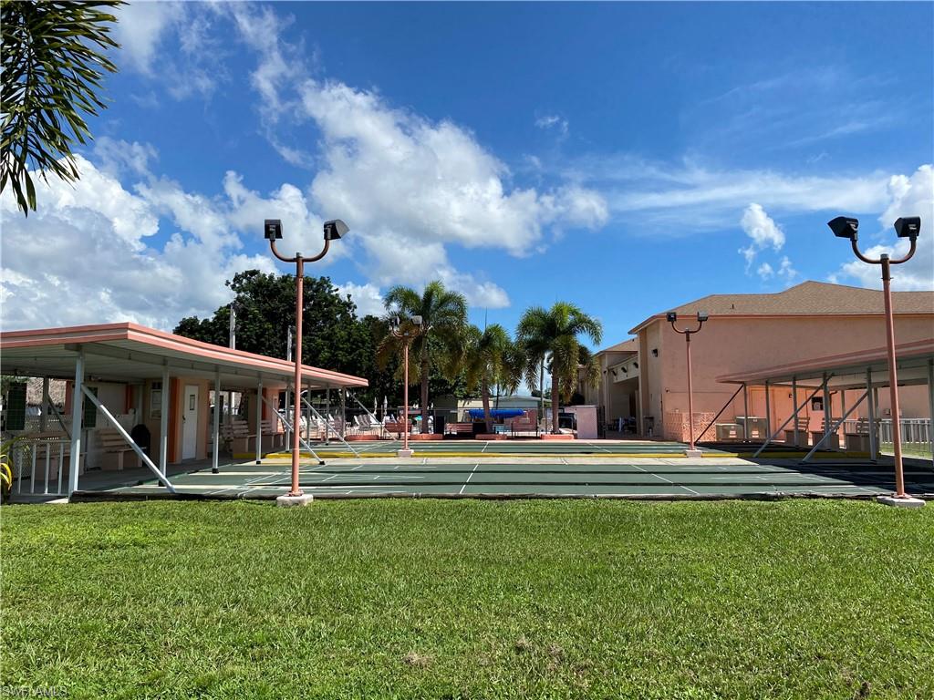 Outdoor recreation area featuring multiple courts, covered seating structures, and mature palm trees
