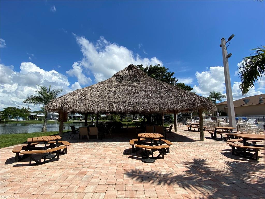 Expansive outdoor pavilion featuring a thatched roof, brick paver patio, and multiple picnic tables