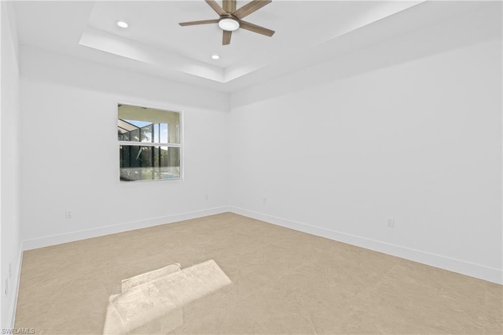 Empty room featuring a raised ceiling, recessed lighting, and a ceiling fan