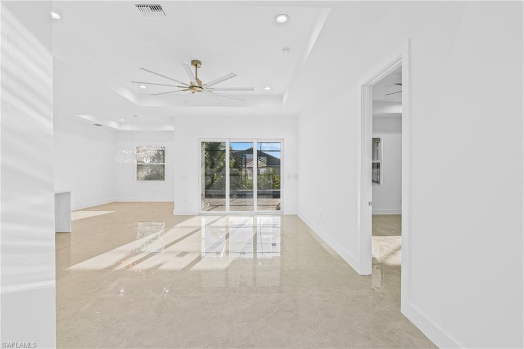 Spare room with a tray ceiling, a chandelier, recessed lighting, and ceiling fan