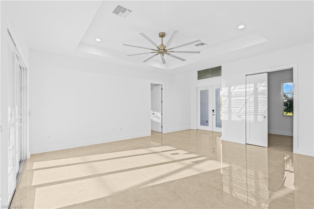Empty room featuring french doors, a tray ceiling, ceiling fan, and recessed lighting