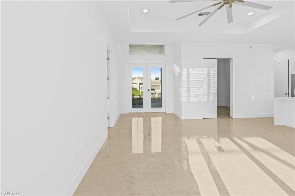 Spare room with a tray ceiling, french doors, light tile patterned flooring, ceiling fan, and recessed lighting