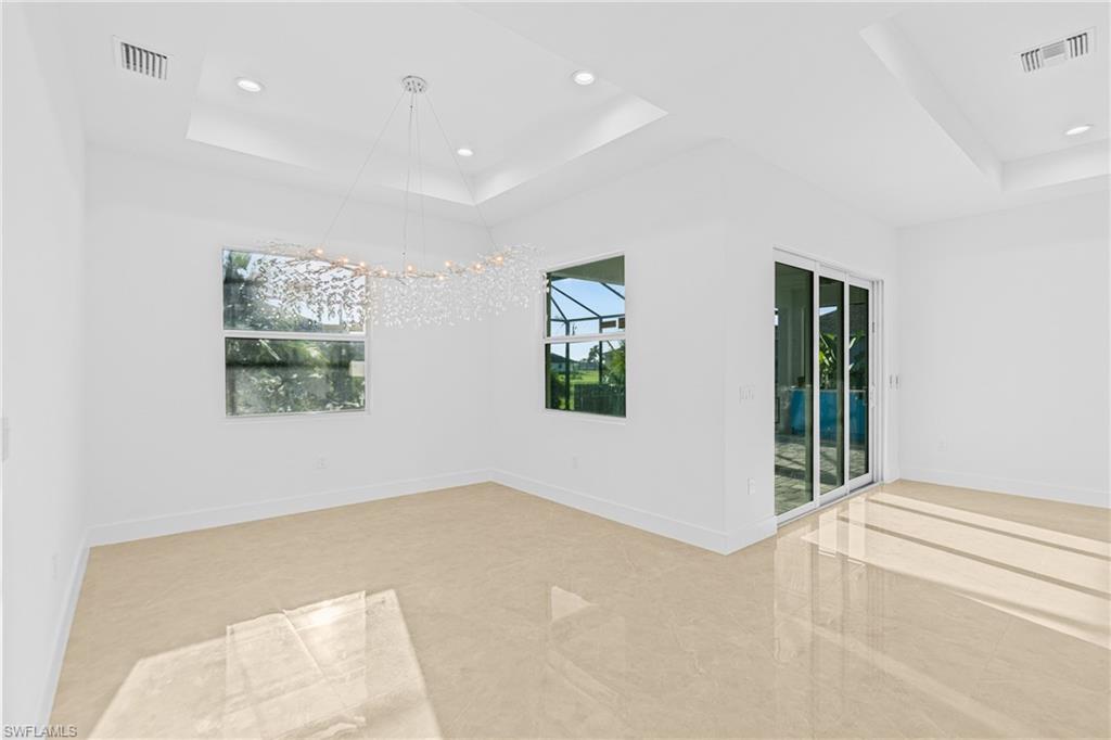 Spare room with a raised ceiling, recessed lighting, and a chandelier