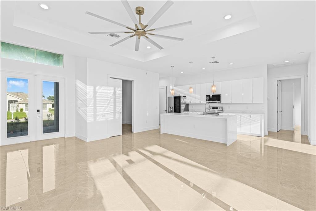 Unfurnished living room featuring a raised ceiling, french doors, recessed lighting, and a ceiling fan
