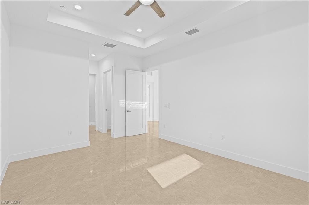 Unfurnished bedroom with ceiling fan, recessed lighting, a closet, a raised ceiling, and light tile patterned floors
