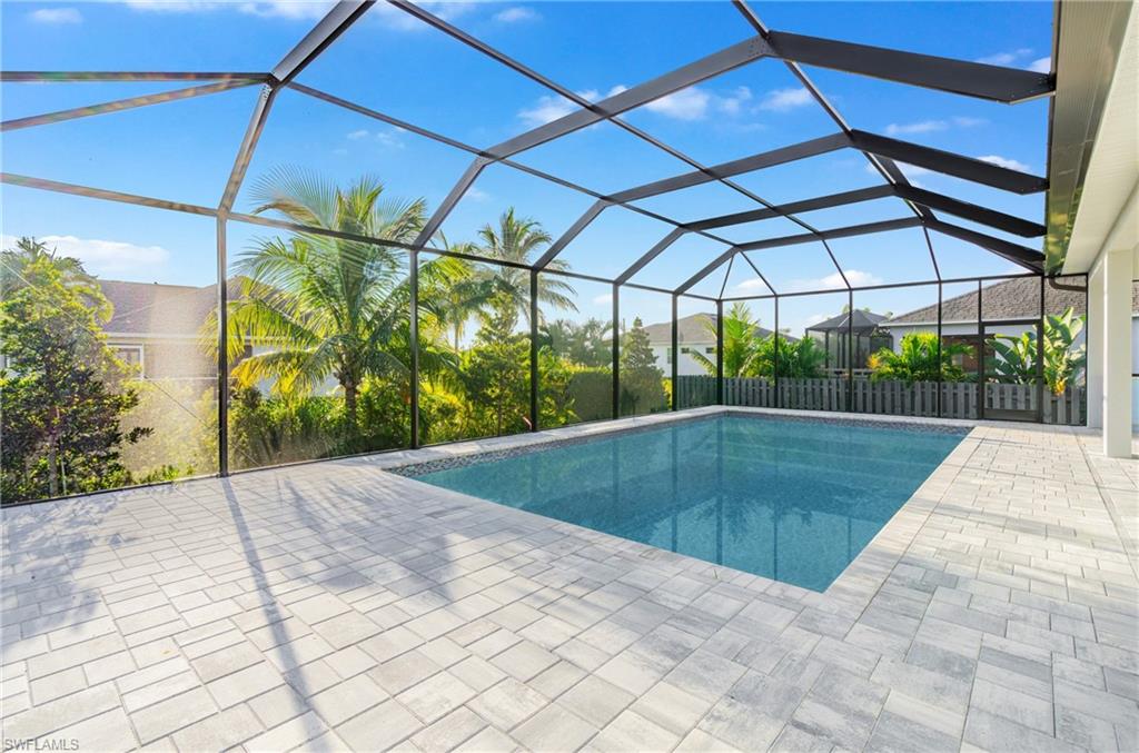 Outdoor pool featuring a sunroom, glass enclosure, and a patio