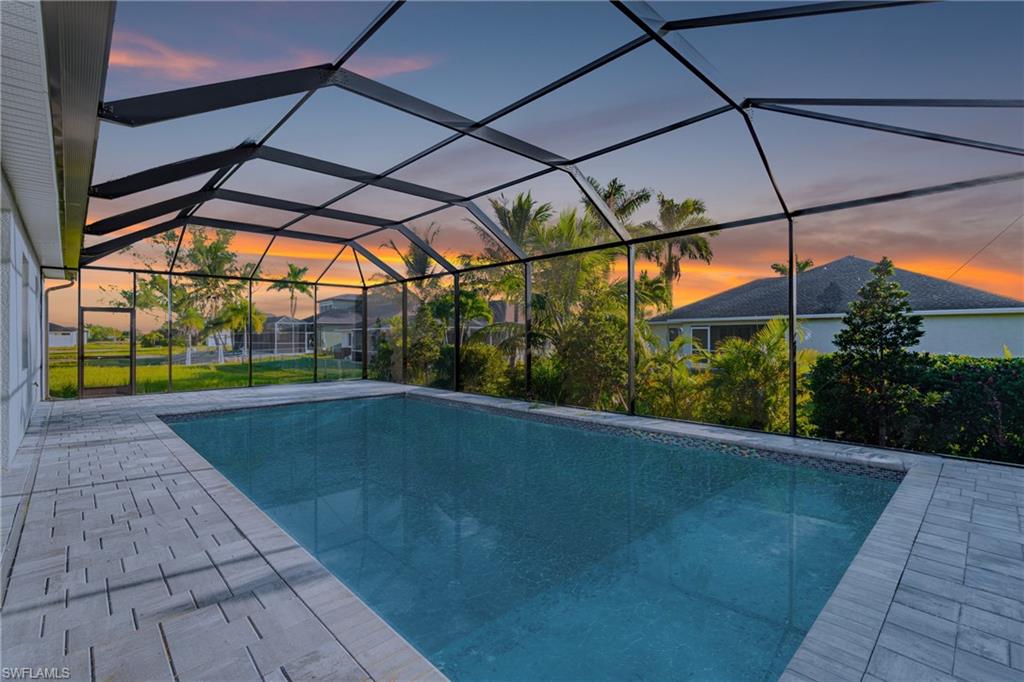Pool at dusk with an outdoor pool, a sunroom, and a lanai