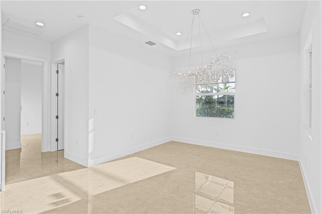 Empty room featuring a raised ceiling, recessed lighting, and light tile patterned floors