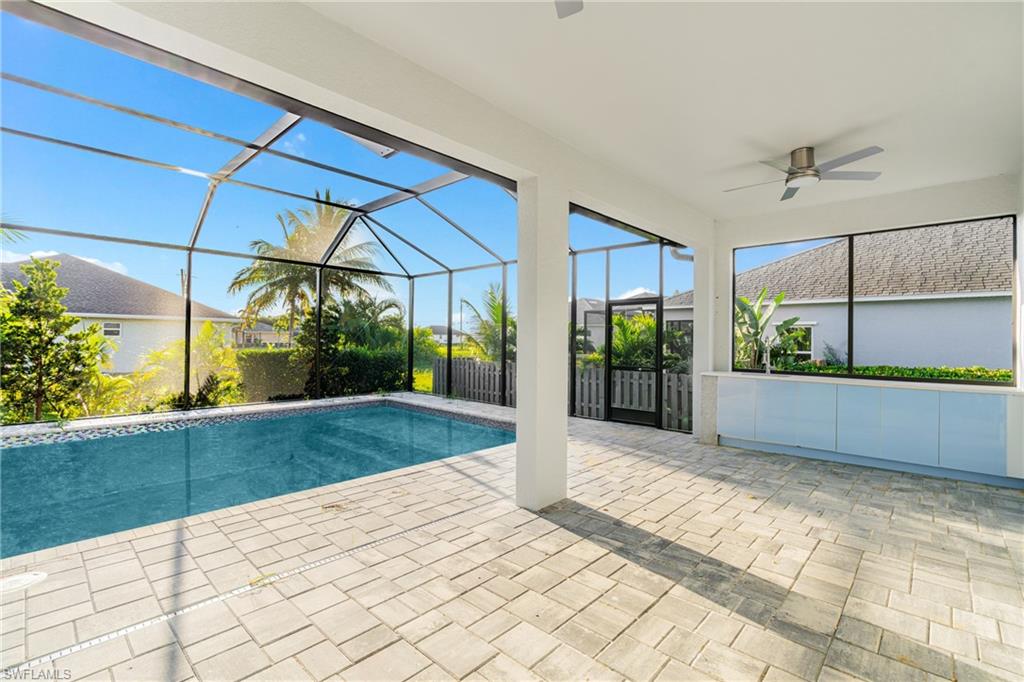 Swimming pool featuring glass enclosure, ceiling fan, a patio area, and a sunroom